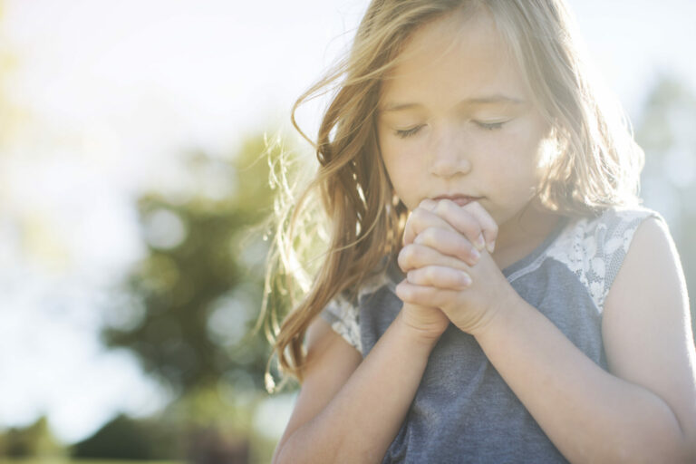 Little girl praying with folded hands