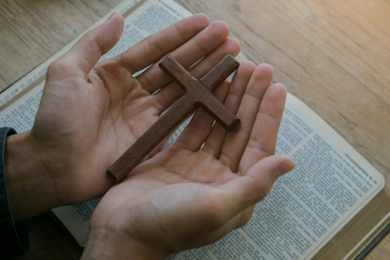 Christian man holding jesus cross.Hands folded in prayer on a Holy Bible