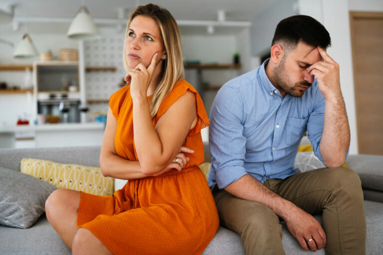 Sad pensive couple thinking of relationships problems sitting on sofa