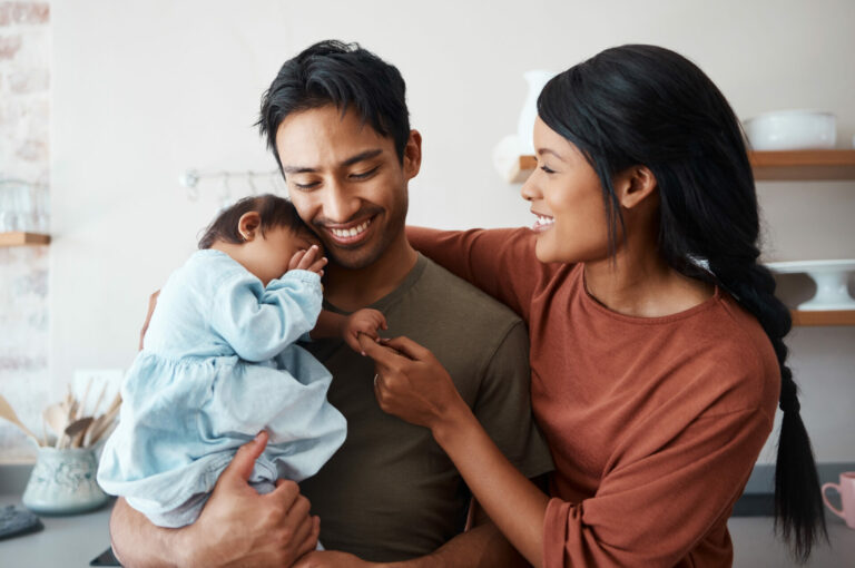 Love, baby and happy parents bonding and caring for their infant child in their comfy home.